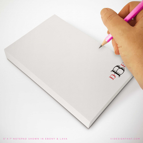 Personalized notepad with modern monogram in ebony and lava ink, shown in use with pink pencil on premium writing paper.